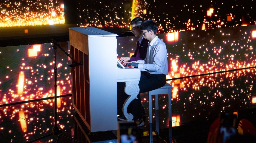 智能仿生手使用者古月與少年鋼琴家舒海峰合奏。主辦方供圖